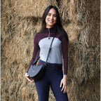 Woman in equestrian attire standing in front of hay bales