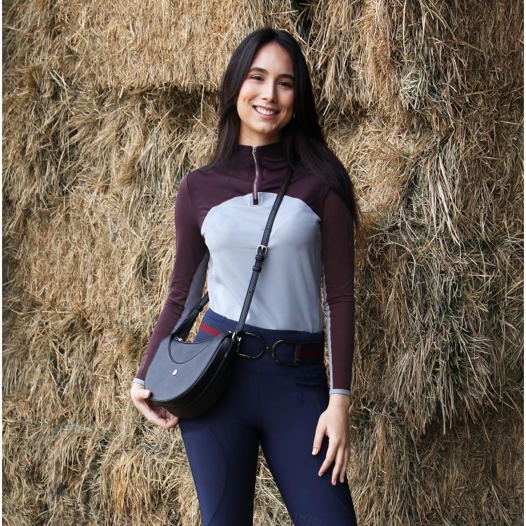 Woman in equestrian attire standing in front of hay bales