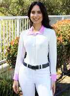 Woman wearing a white equestrian outfit with pink accents outdoors.