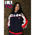Person wearing a navy, white, and red jacket with LAEQ logo on a hay background
