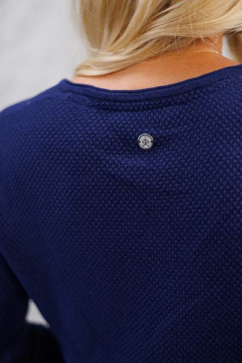 Close-up of a person wearing a blue textured sweater with a button detail.