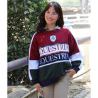 Person wearing a maroon and green 'Equestria' sweater outdoors.