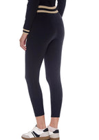 Person wearing black leggings with beige stripes on a white background