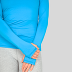 Person wearing a blue long-sleeve shirt with sleeves rolled up on a gray background