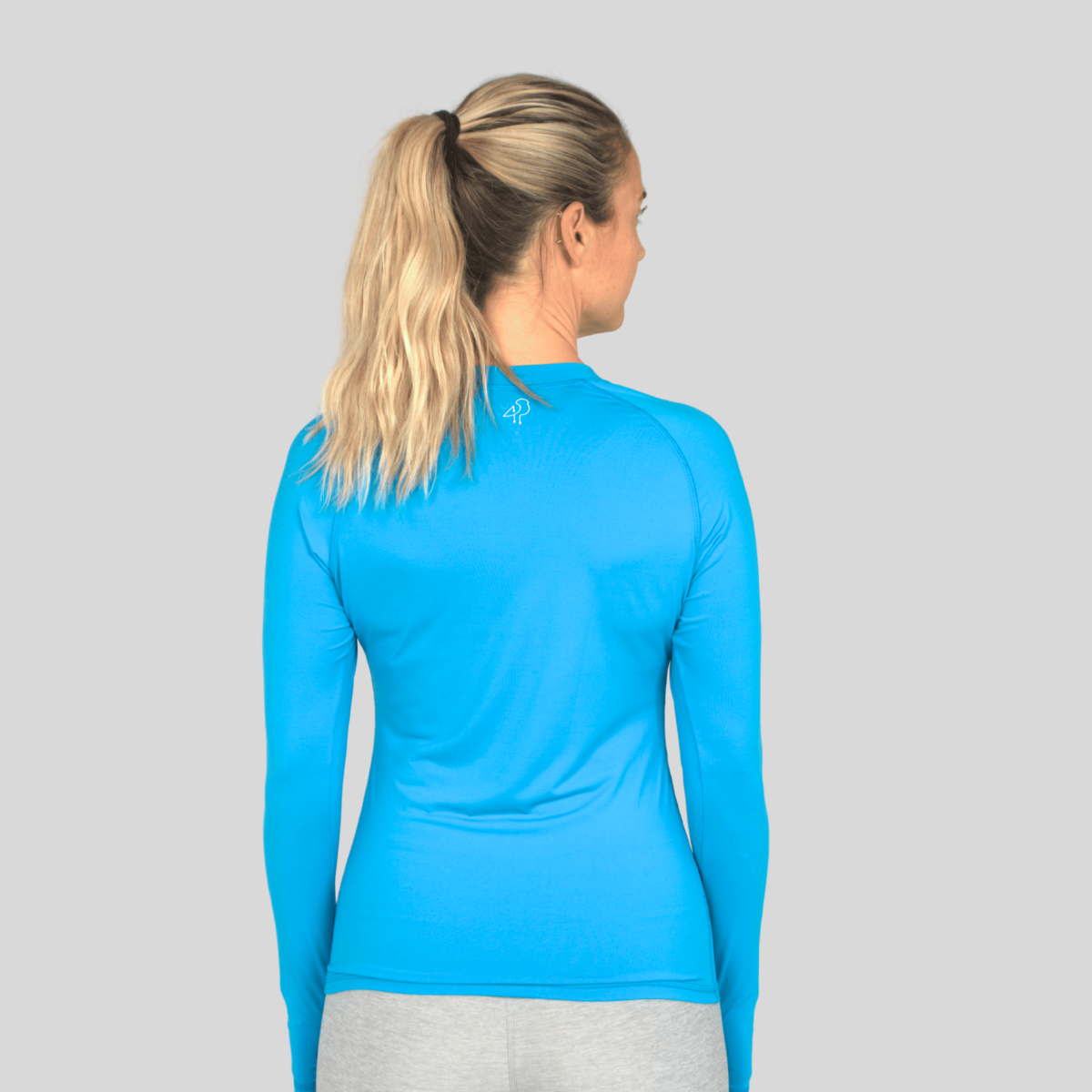 Woman wearing a blue long-sleeve athletic shirt on a gray background
