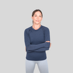 Woman wearing a blue long-sleeve shirt against a gray background