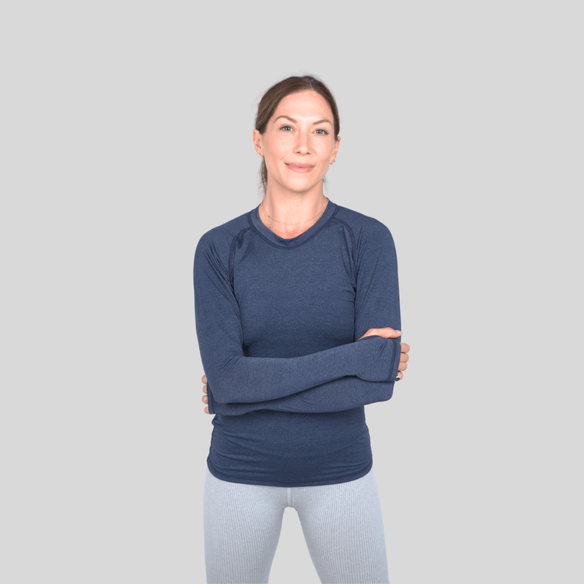 Woman wearing a blue long-sleeve shirt against a gray background