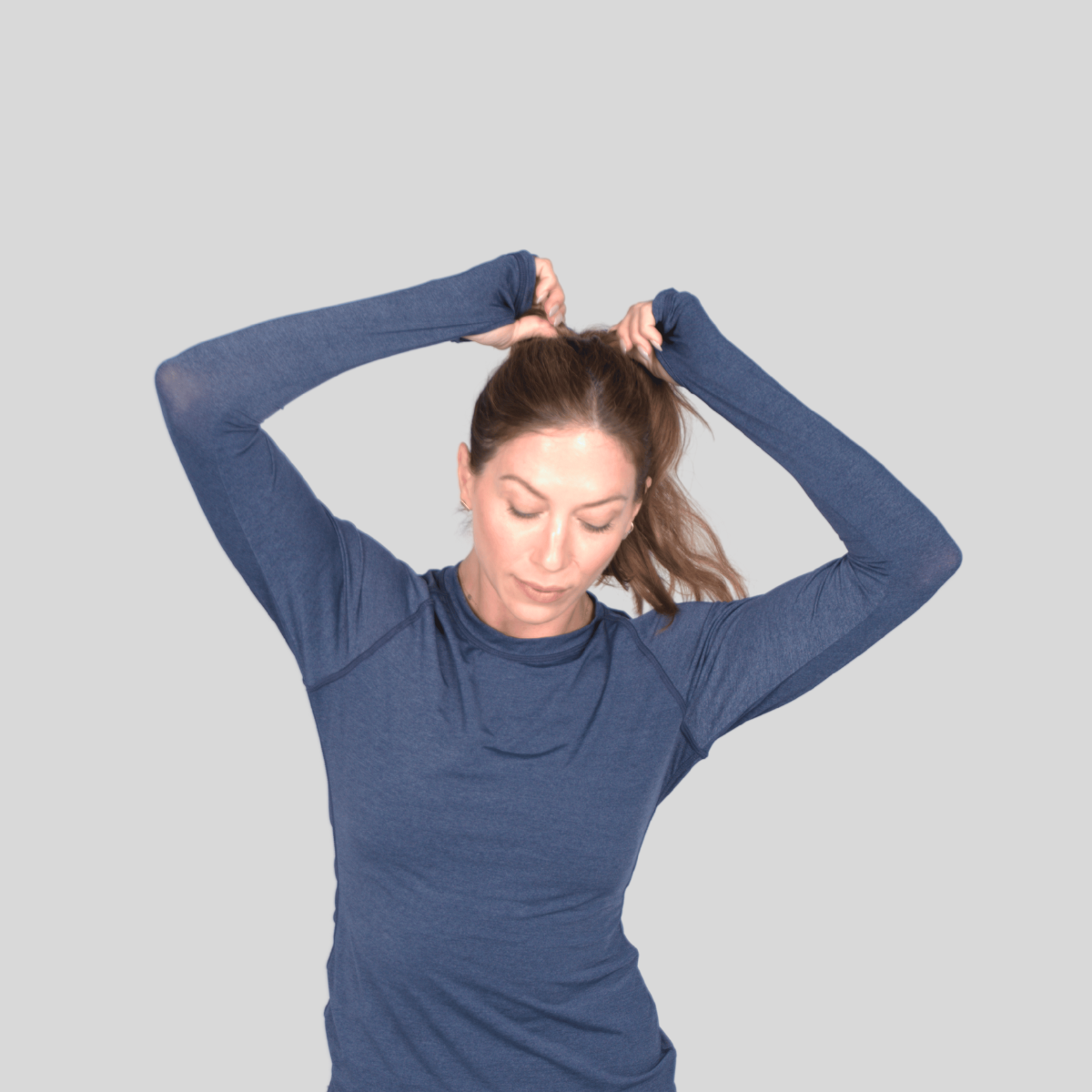 Person wearing a blue long-sleeve shirt against a gray background