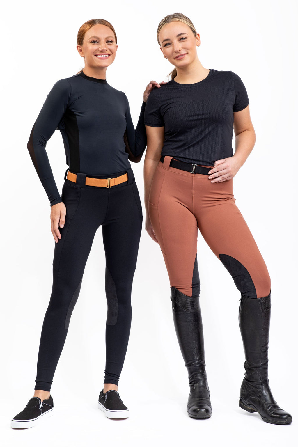 Two women wearing equestrian attire with black and brown pants on a white background