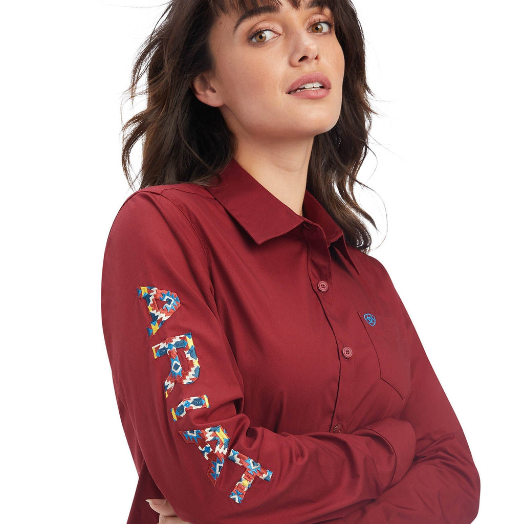 Woman wearing a red shirt with colorful floral embroidery on sleeves against a white background