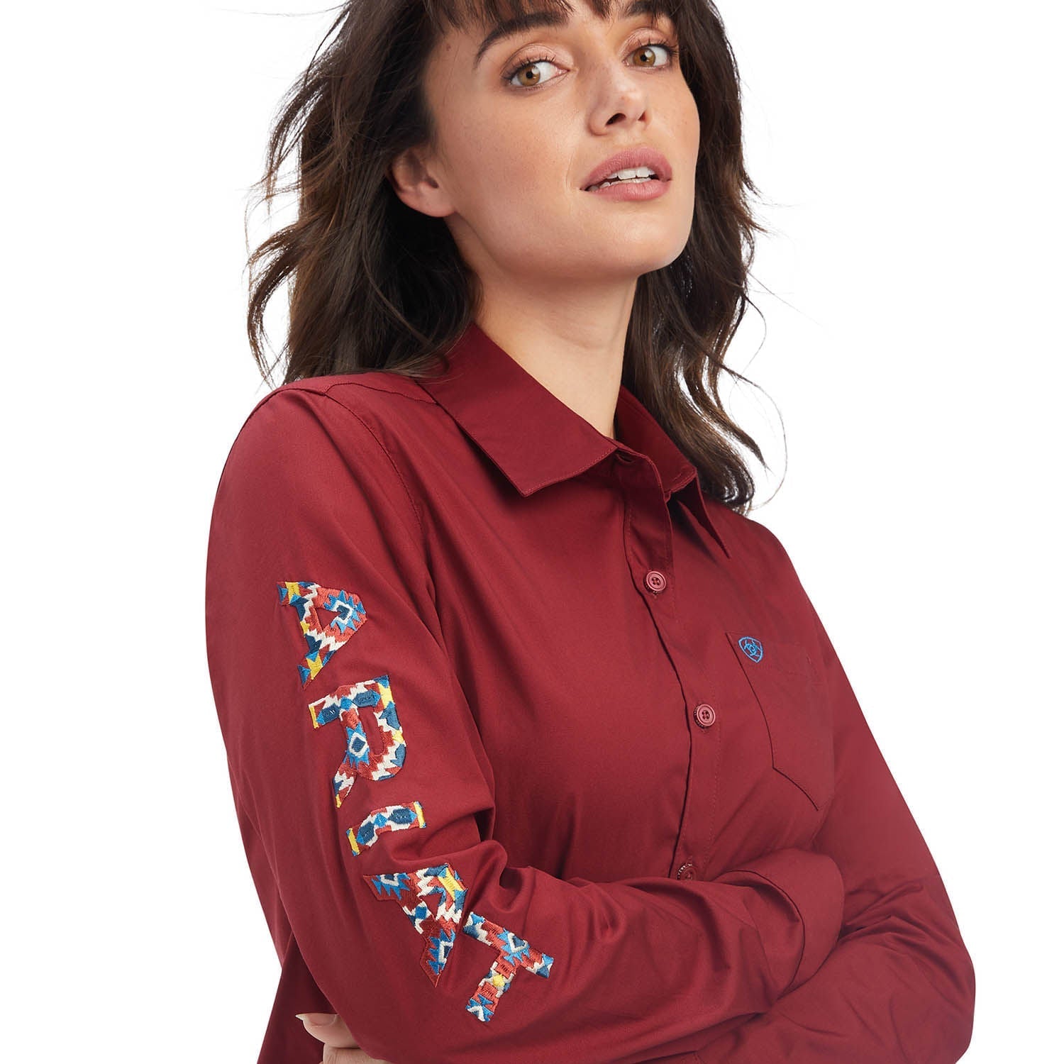 Woman wearing a red shirt with colorful floral embroidery on sleeves against a white background
