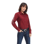 Woman wearing a red shirt with floral embroidery on sleeves against a white background