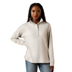 Woman wearing a beige long-sleeve shirt with a quarter zip on a white background