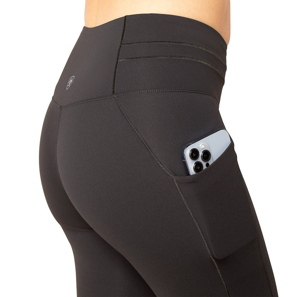 Black leggings with a pocket holding electronic devices on a white background
