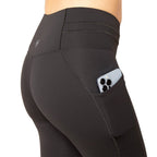 Black leggings with a pocket holding electronic devices on a white background