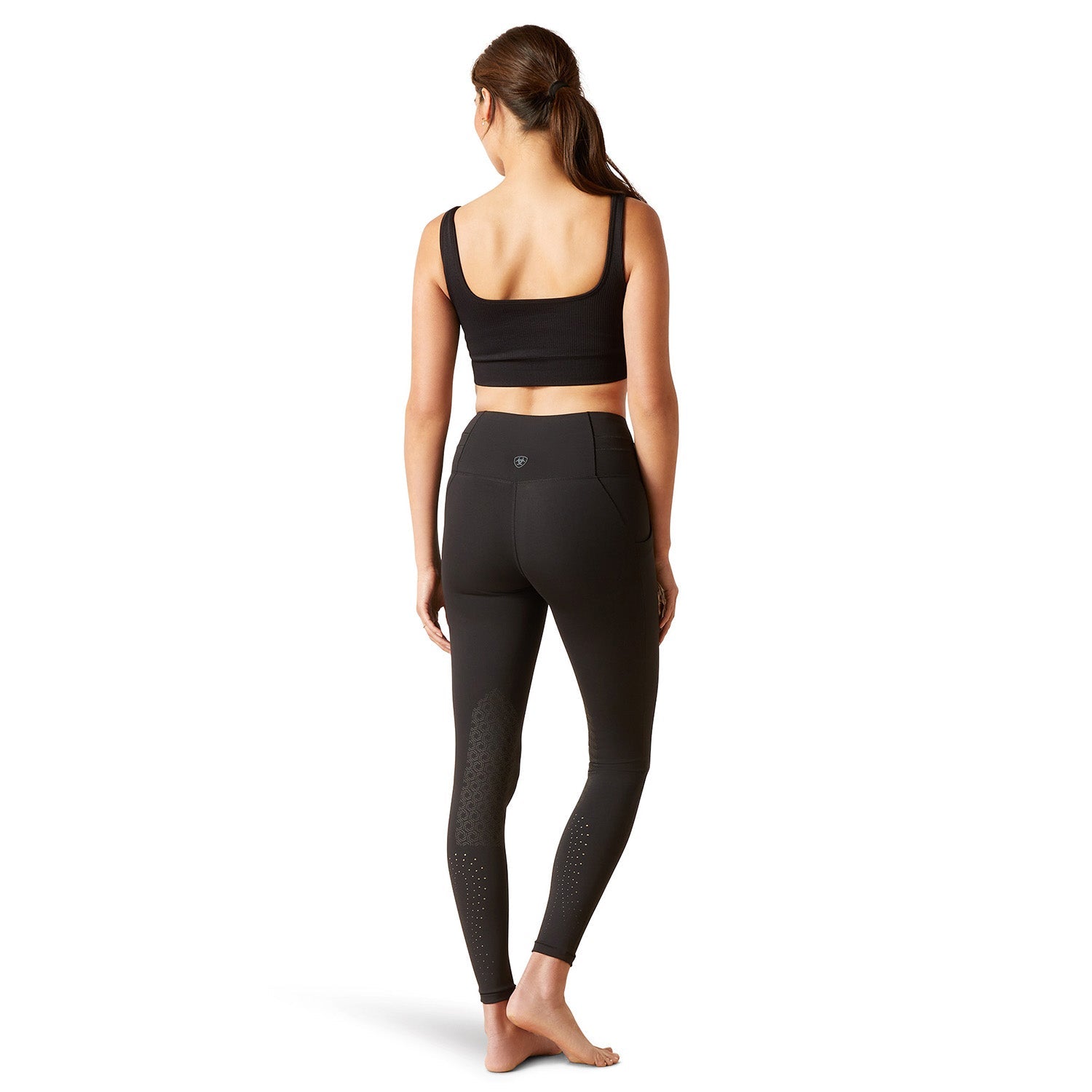 Woman wearing black athletic leggings and sports bra on a white background