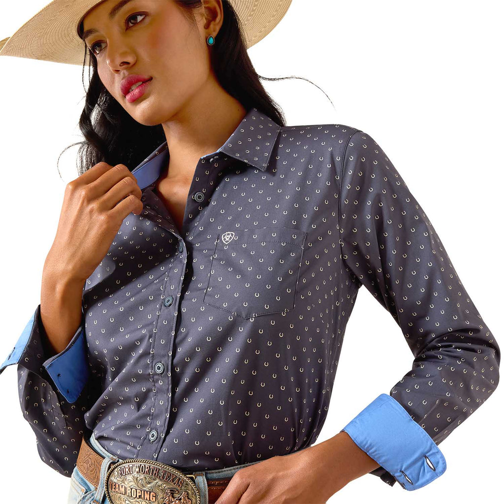 Woman wearing a patterned shirt with rolled-up sleeves and a cowboy hat on a white background