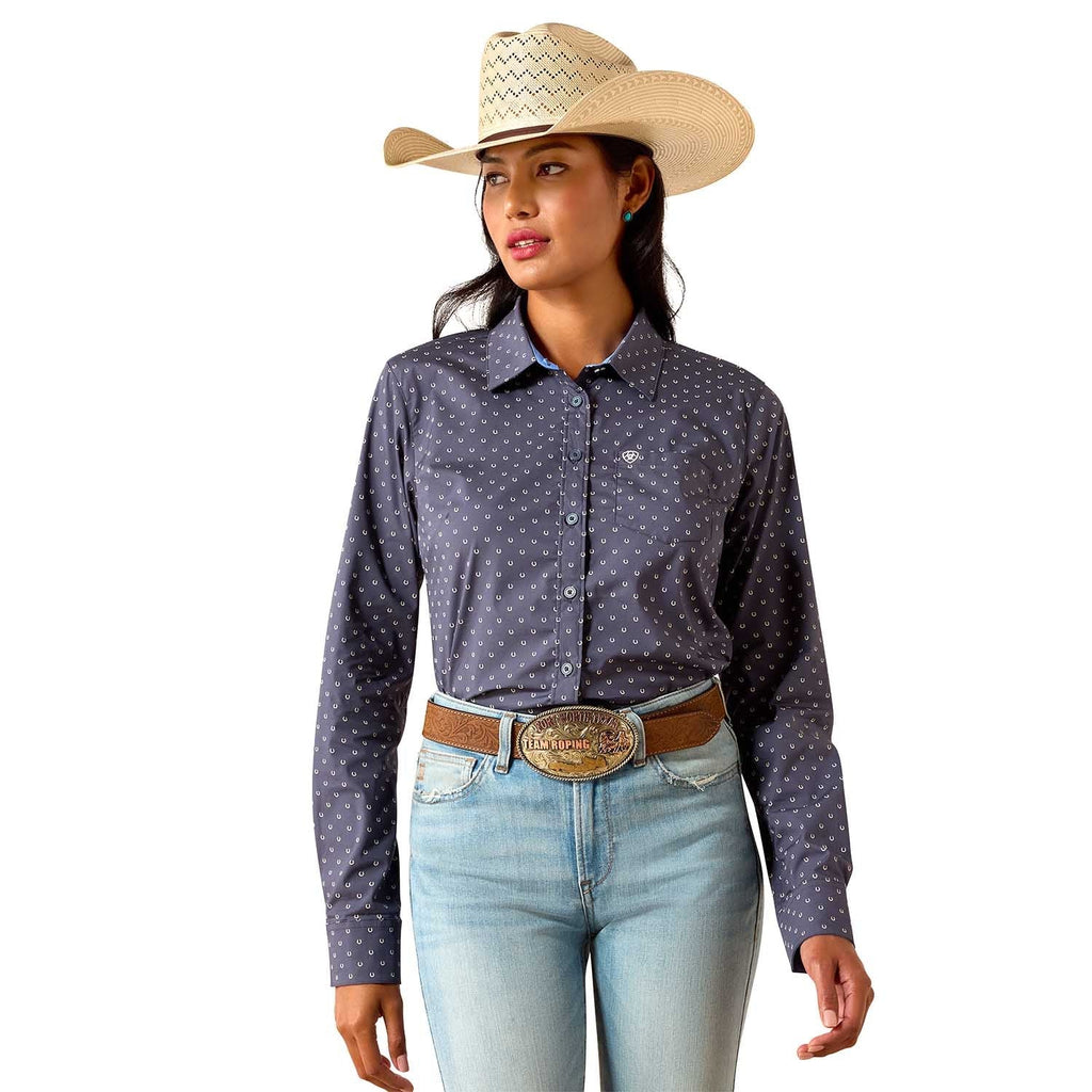 Woman wearing a patterned long-sleeve shirt, jeans, and a cowboy hat on a white background
