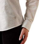 Close-up of a person wearing a beige striped shirt with a brand logo on a white background