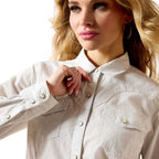 Woman wearing a light-colored denim shirt with a white background