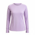 Woman wearing a light purple long-sleeve top with colorful leggings on a white background