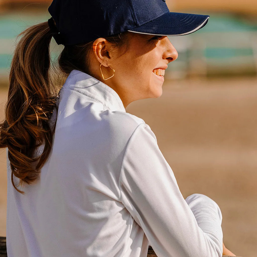 Woman wearing a navy cap and white shirt outdoors