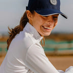 Woman wearing a navy cap and white jacket outdoors