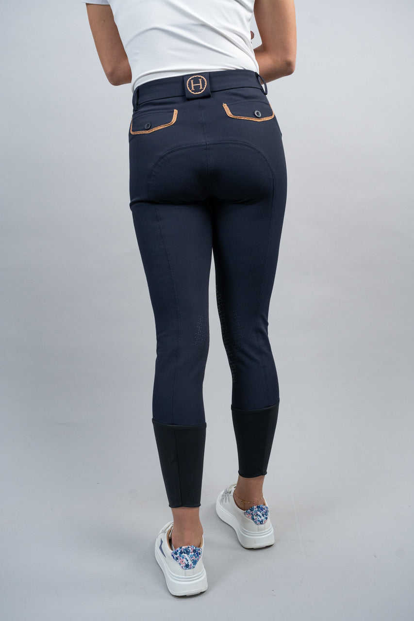 Person wearing navy riding pants with a white background