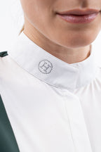 Close-up of a womens green show top with white collar that has a logo on the collar worn by a person.