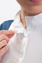 Person adjusting the collar of a white shirt against a neutral background