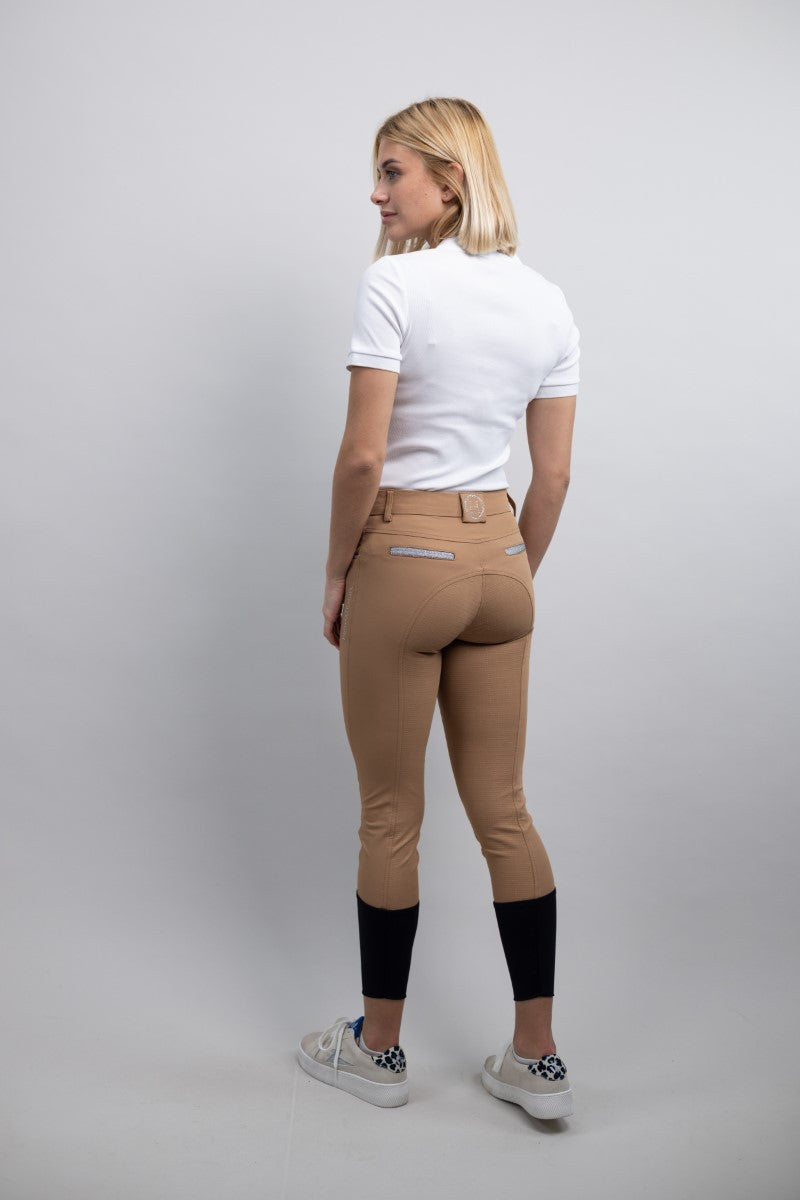 Woman wearing tan riding pants with a white background
