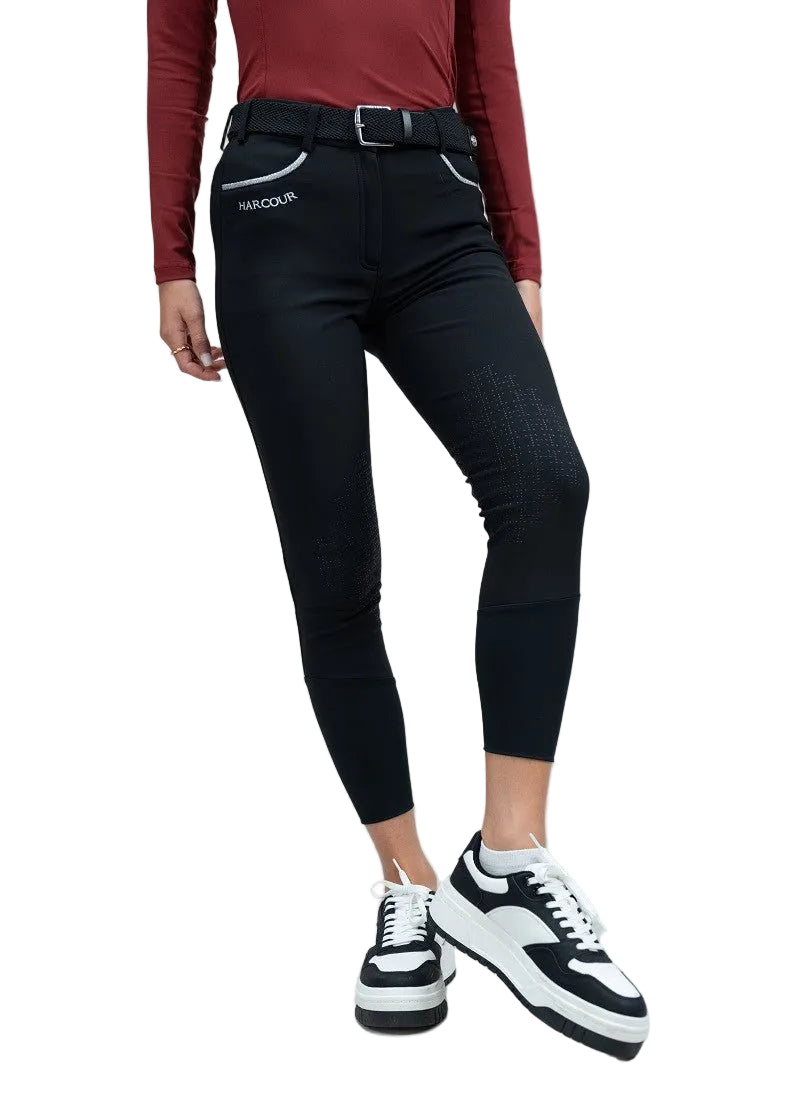 Person wearing black riding pants with a visible brand logo on a gray background