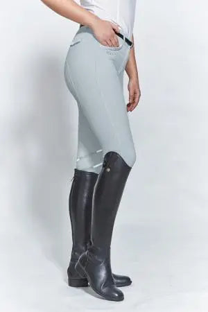 Person wearing light gray riding pants and black riding boots on a white background
