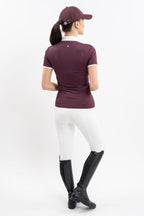Person wearing a maroon equestrian shirt, white pants, and black boots on a white background