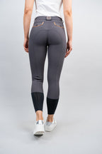 Person wearing gray riding pants with black ankle cuff on a light gray background