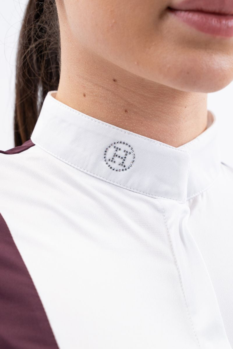 Close-up of a person wearing a white shirt with a logo on the collar.