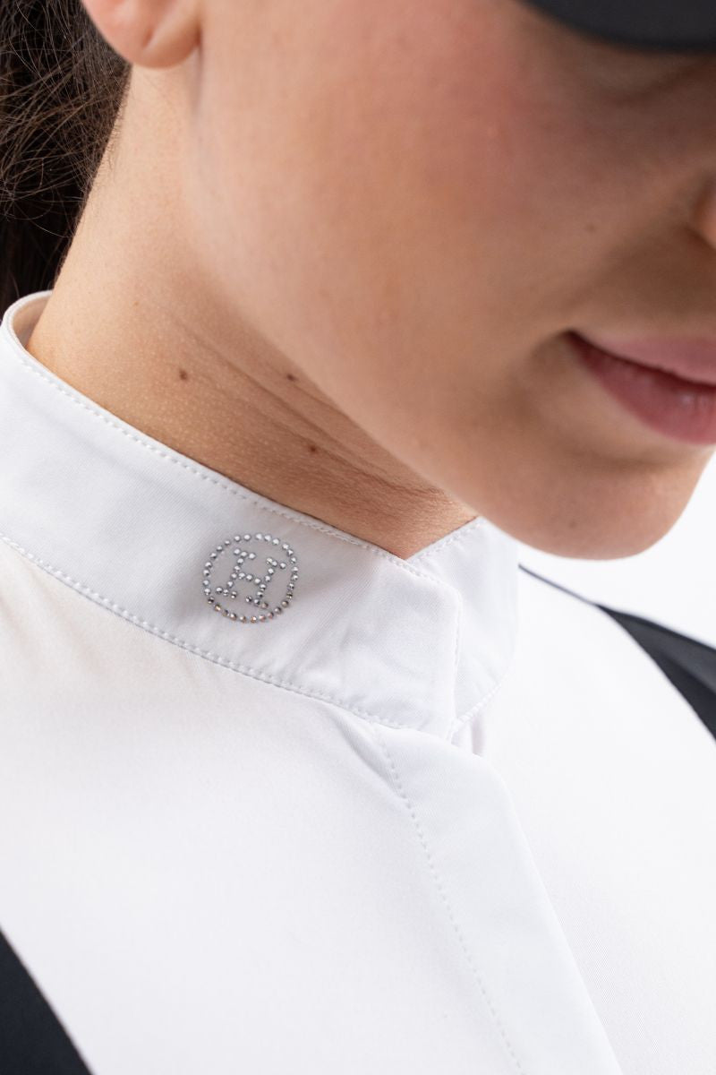 Close-up of a person wearing a white shirt with a small decorative button on the collar.