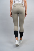 Beige riding pants with black ankle cuff by a person on a gray background