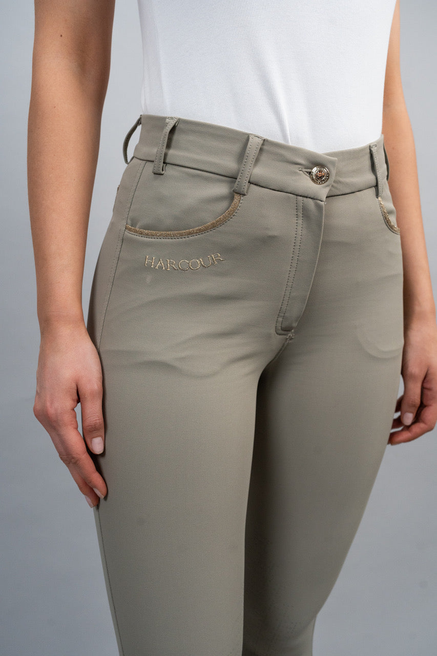 Beige riding pants with a visible brand logo on a gray background