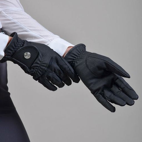 a womans hands trying on black equestrian gloves 